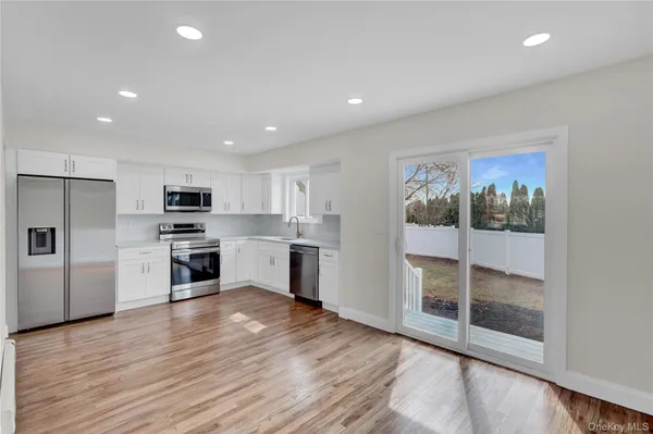 a large white kitchen with stainless steel appliances granite countertop a stove and a refrigerator