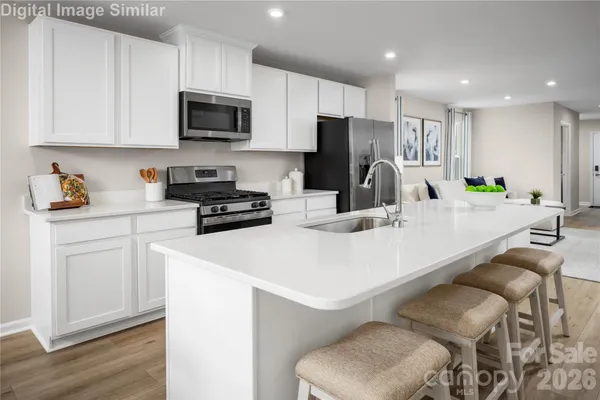 a kitchen with a sink a microwave a refrigerator and white cabinets