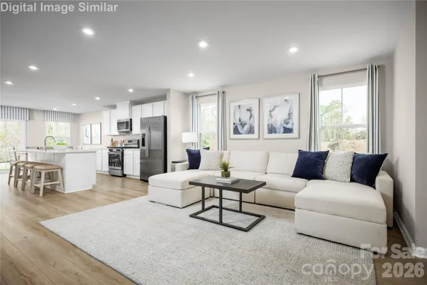 a living room with furniture and kitchen view with wooden floor