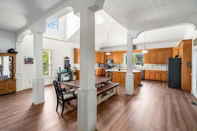 a kitchen with stainless steel appliances a dining table chairs stove refrigerator and cabinets