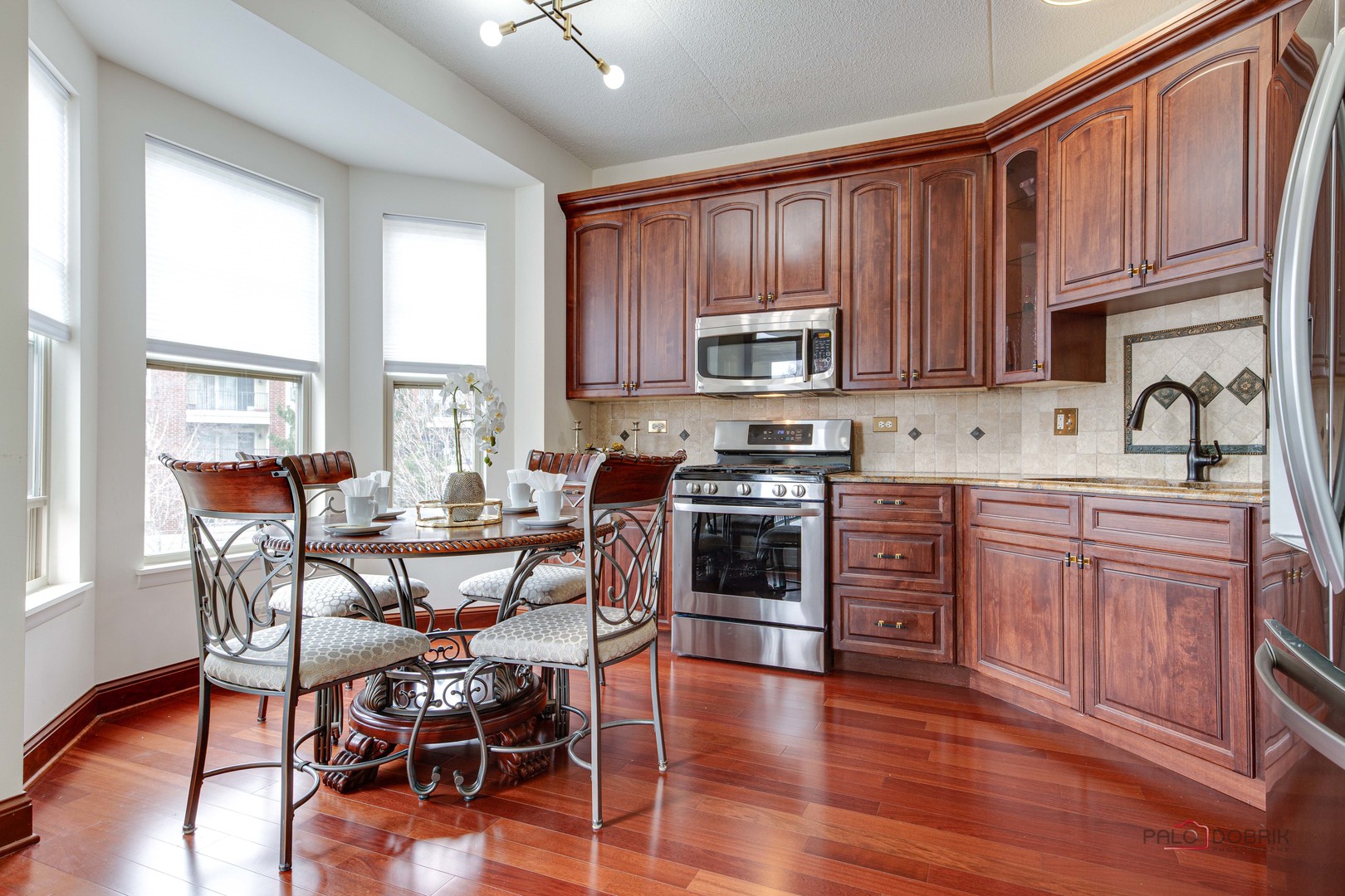 720 Prestwick Lane, Unit 302 Wheeling, IL 60090 - Photo 6 of 23 a kitchen with stainless steel appliances a stove a sink a microwave and wooden cabinets