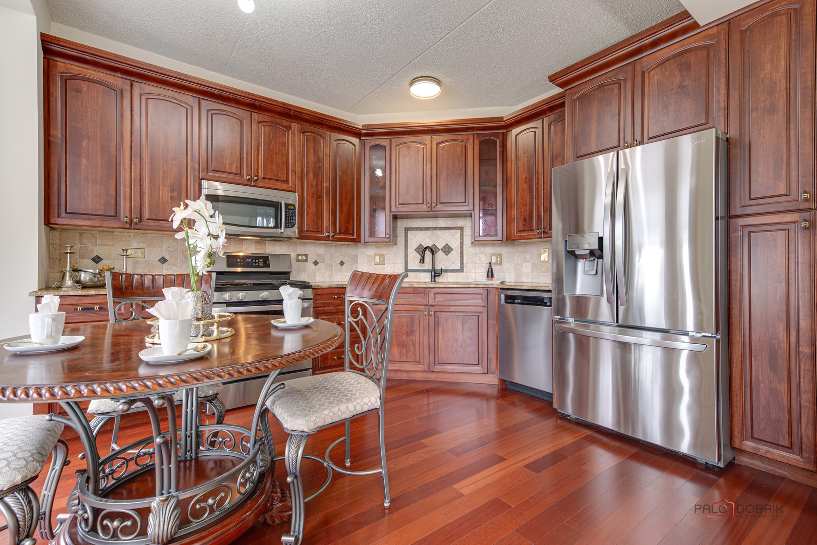720 Prestwick Lane, Unit 302 Wheeling, IL 60090 - Photo 7 of 23 a kitchen with granite countertop wooden floors white cabinets and stainless steel appliances