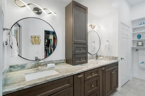 a bathroom with a granite countertop double vanity sink and a mirror