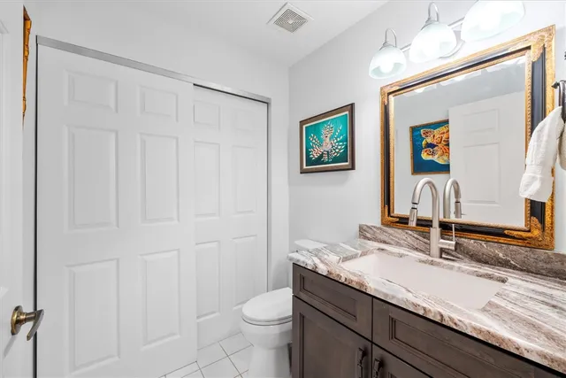 a bathroom with a granite countertop sink vanity mirror and toilet