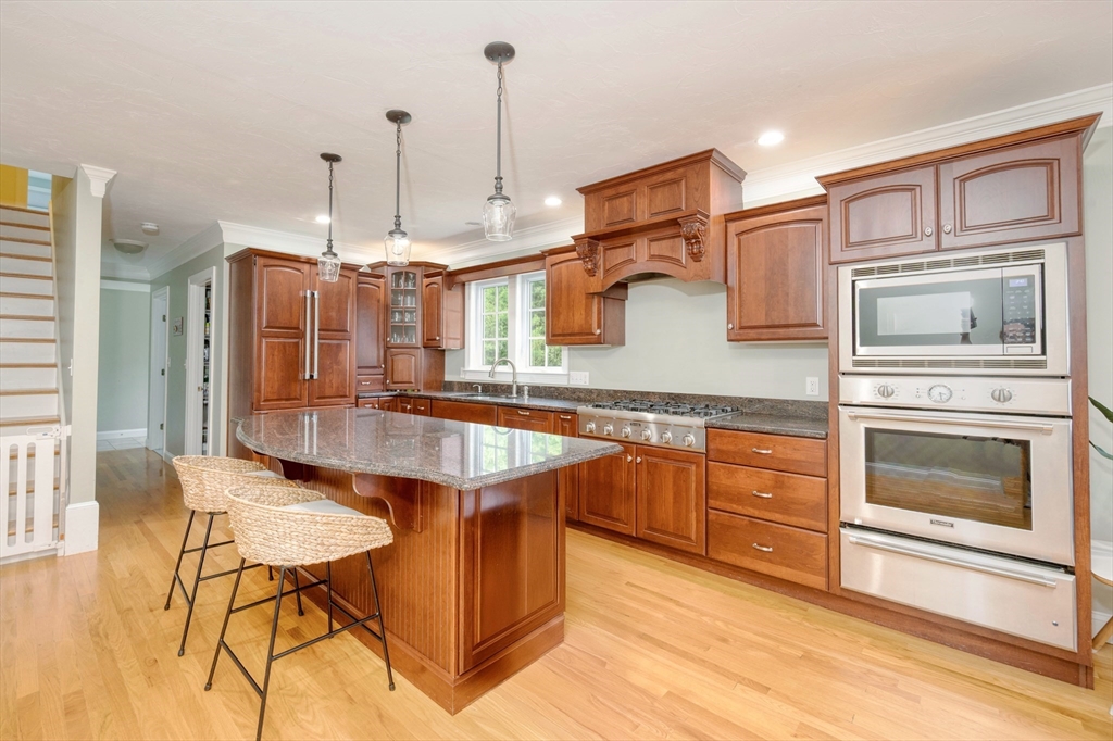 182 Jean Carol Road Abington, MA 02351 - Photo 13 of 38 a kitchen with stainless steel appliances kitchen island granite countertop a table chairs in it and wooden floors