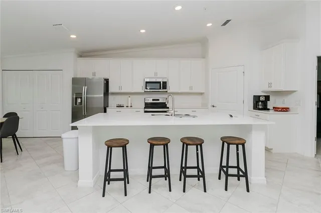 a kitchen with stainless steel appliances granite countertop a table chairs refrigerator and sink