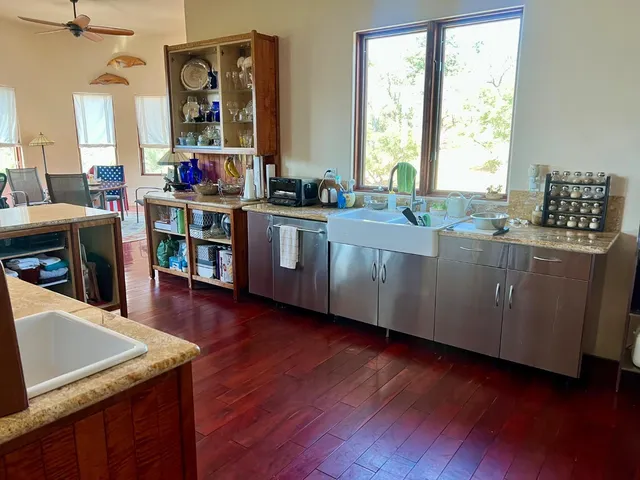 a kitchen with stainless steel appliances granite countertop a sink a stove a wooden floor and a large window