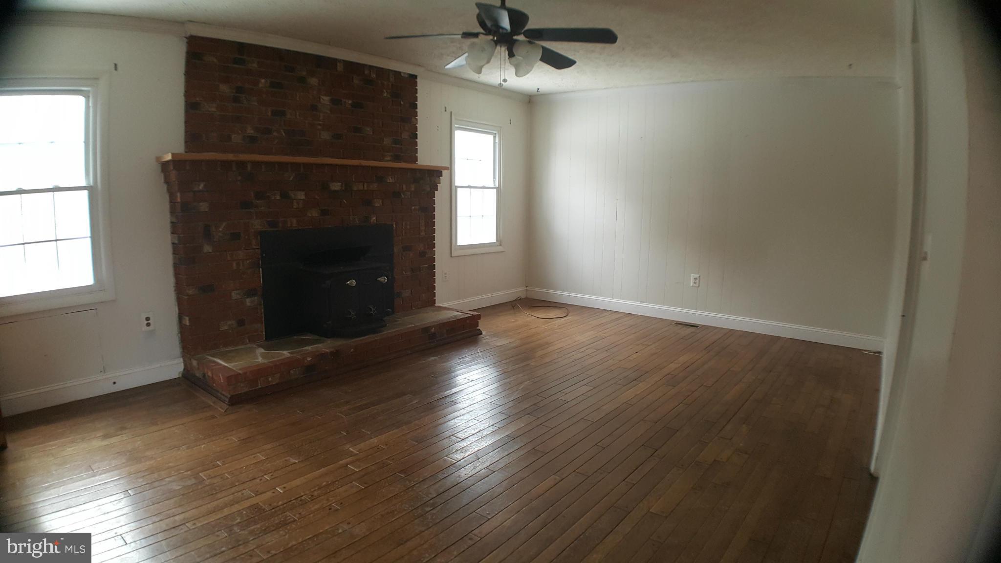 5794 Howellsville Road Front Royal, VA 22630 - Photo 8 of 21 an empty room with wooden floor a fireplace and windows