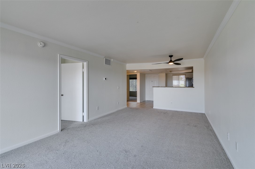 8070 West Russell Road, Unit 2026 Las Vegas, NV 89113 - Photo 23 of 41 A well-lit main living space offers comfortable carpeting and a modern ceiling fan.