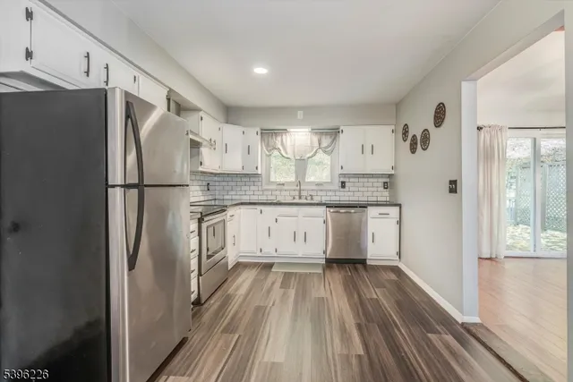 a kitchen with a refrigerator a sink and dishwasher with white cabinets