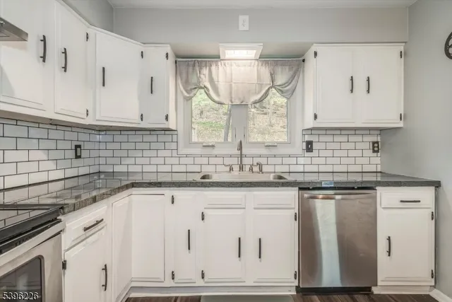 a kitchen with granite countertop white cabinets white appliances and a sink