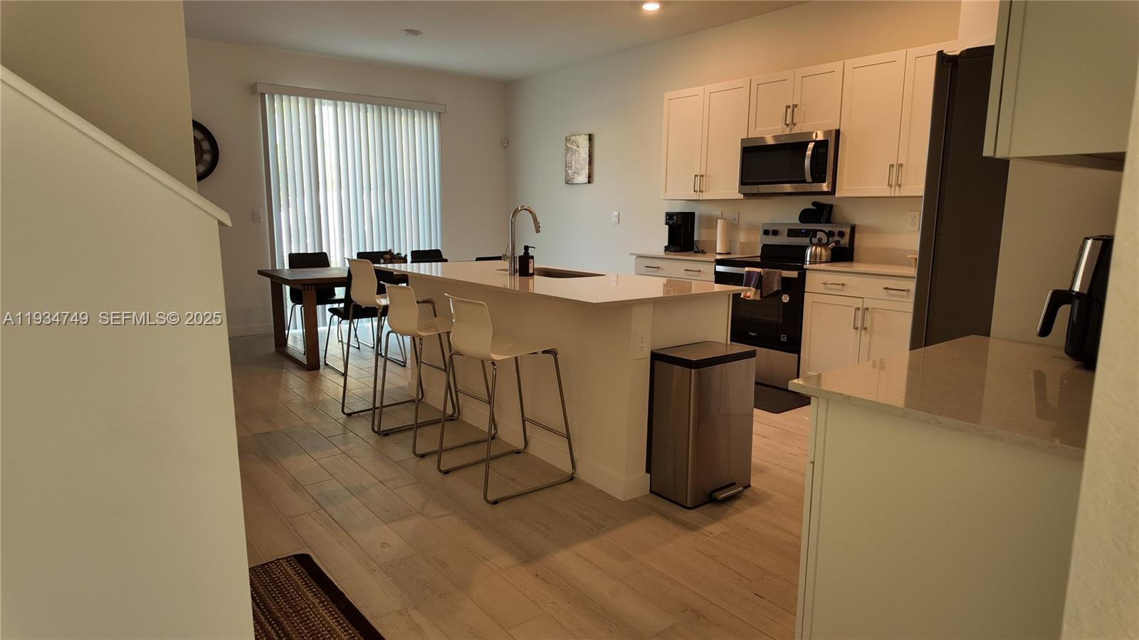 12913 Southwest 265th Terrace, Unit 1 Homestead, FL 33032 - Photo 4 of 22 a kitchen with refrigerator and chairs