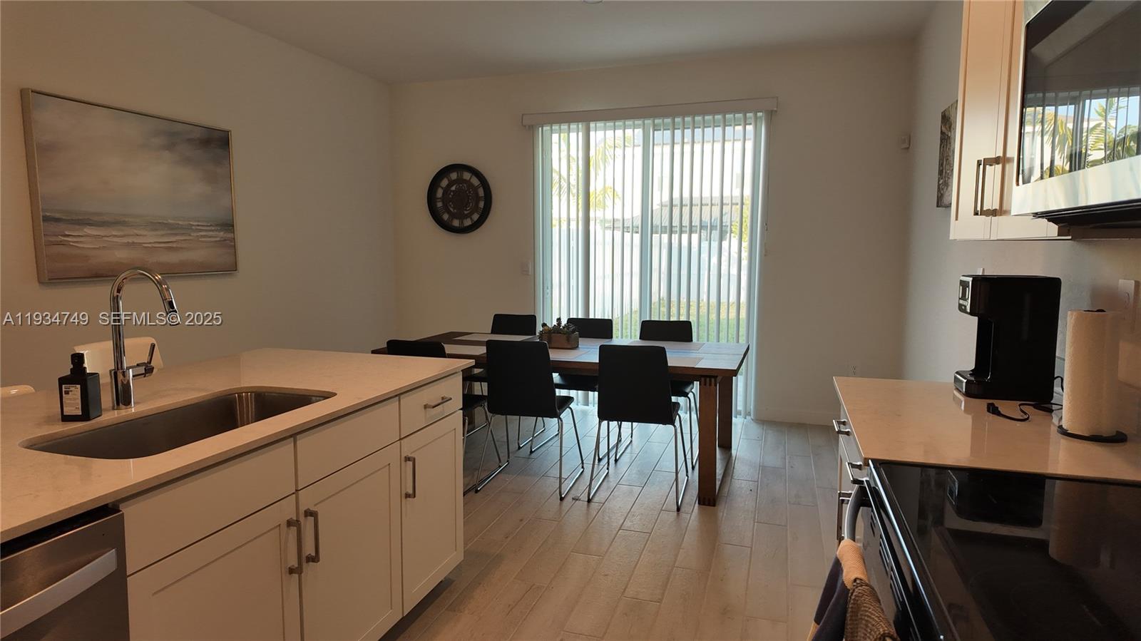 12913 Southwest 265th Terrace, Unit 1 Homestead, FL 33032 - Photo 7 of 22 a kitchen with a sink cabinets and dining table