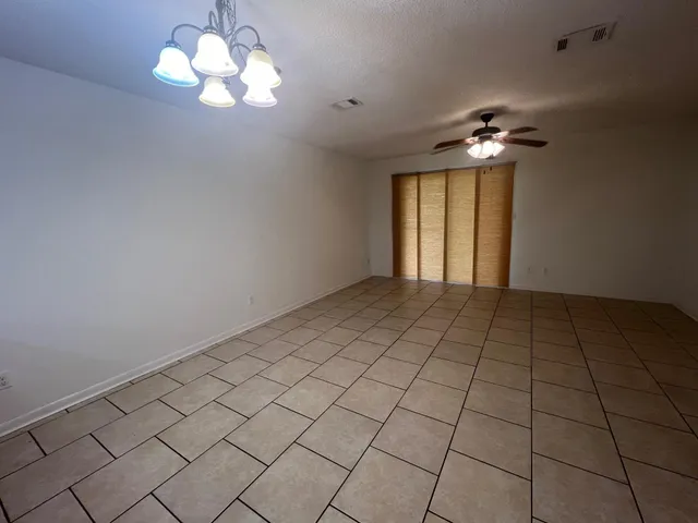 a large room with chandelier fan and kitchen view