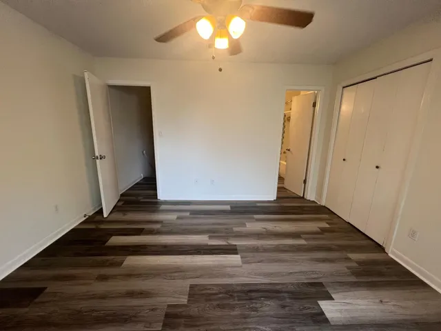 a view of a room with wooden floor and a ceiling fan