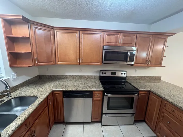 a kitchen with granite countertop a stove top oven microwave and cabinets