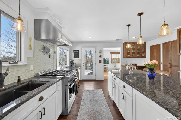 a kitchen with stainless steel appliances granite countertop a sink a stove and a wooden floors