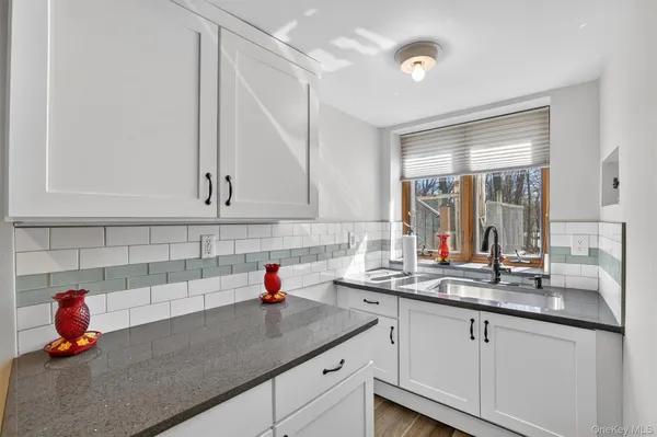 a kitchen with white cabinets and sink