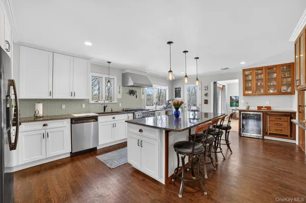 a kitchen with stainless steel appliances kitchen island granite countertop a table chairs sink and cabinets