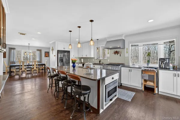 a kitchen with stainless steel appliances a stove a sink a refrigerator and white cabinets with wooden floor