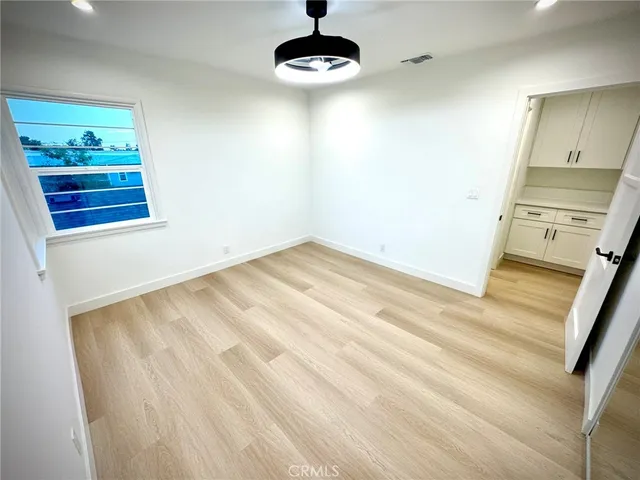 a view of a room with wooden floor and a ceiling fan