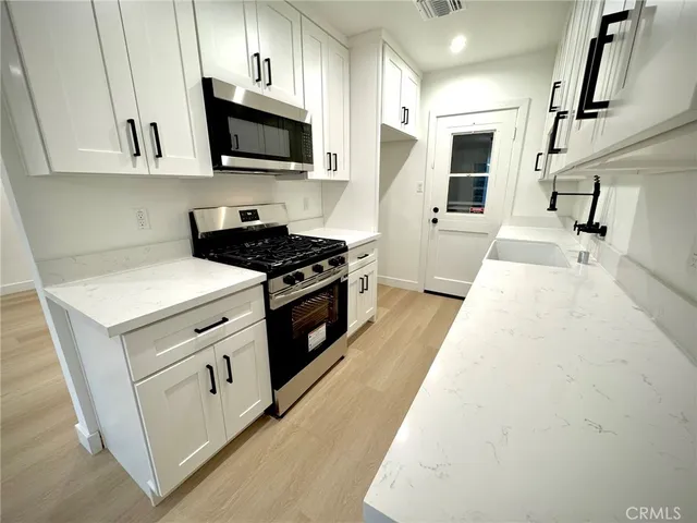 a kitchen with stainless steel appliances granite countertop a stove a sink and a microwave
