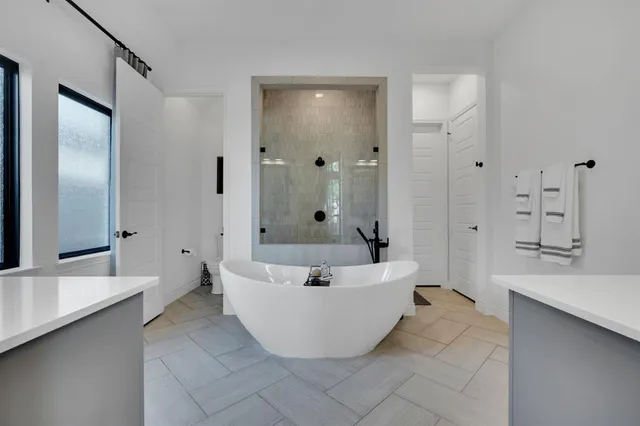 a spacious bathroom with a tub shower and mirror