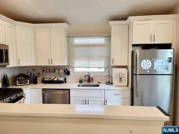 a kitchen with stainless steel appliances a sink a stove a refrigerator a counter space and cabinets
