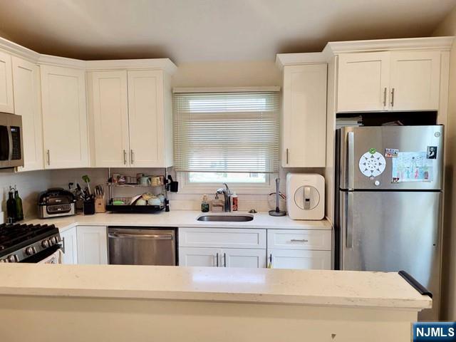 296 County Road, Unit 1 Tenafly, NJ 07670 - Photo 7 of 16 a kitchen with stainless steel appliances a sink a stove a refrigerator a counter space and cabinets