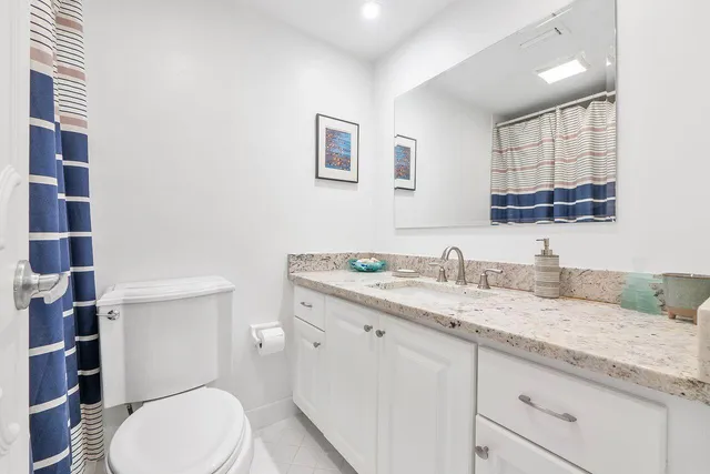a bathroom with a granite countertop toilet sink and mirror