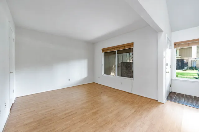 a view of an empty room and bathroom with wooden floor