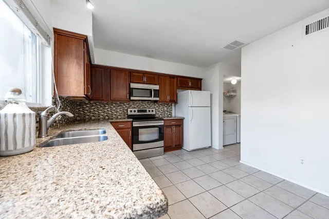 a kitchen with granite countertop a refrigerator and a stove top oven