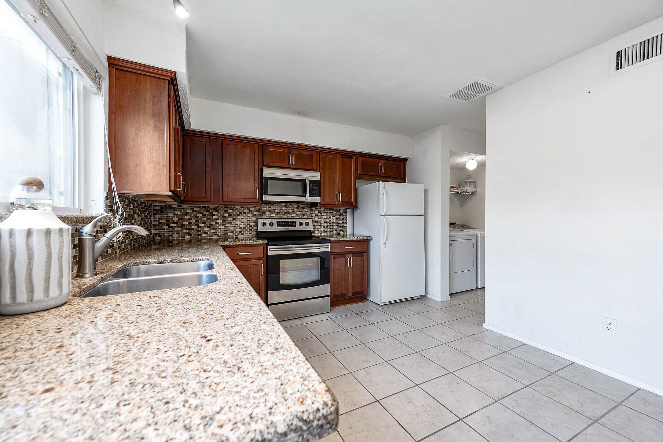 11609 Village Pl Drive Houston, TX 77077 - Photo 15 of 34 a kitchen with granite countertop a refrigerator and a stove top oven