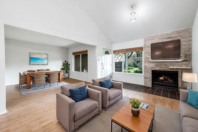 a living room with furniture a fireplace a flat screen tv and a large window
