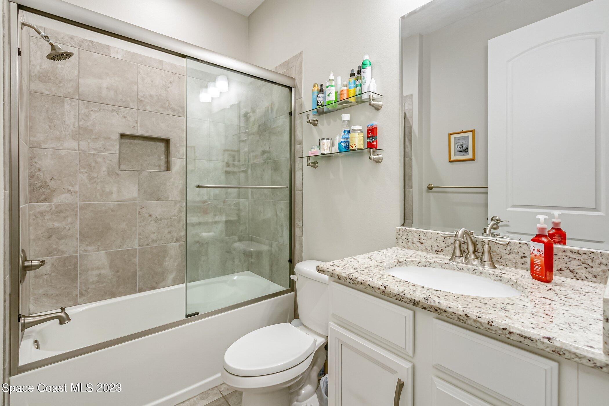 7729 Kerrington Drive Melbourne, FL 32940 - Photo 18 of 61 a bathroom with a granite countertop sink a toilet and shower