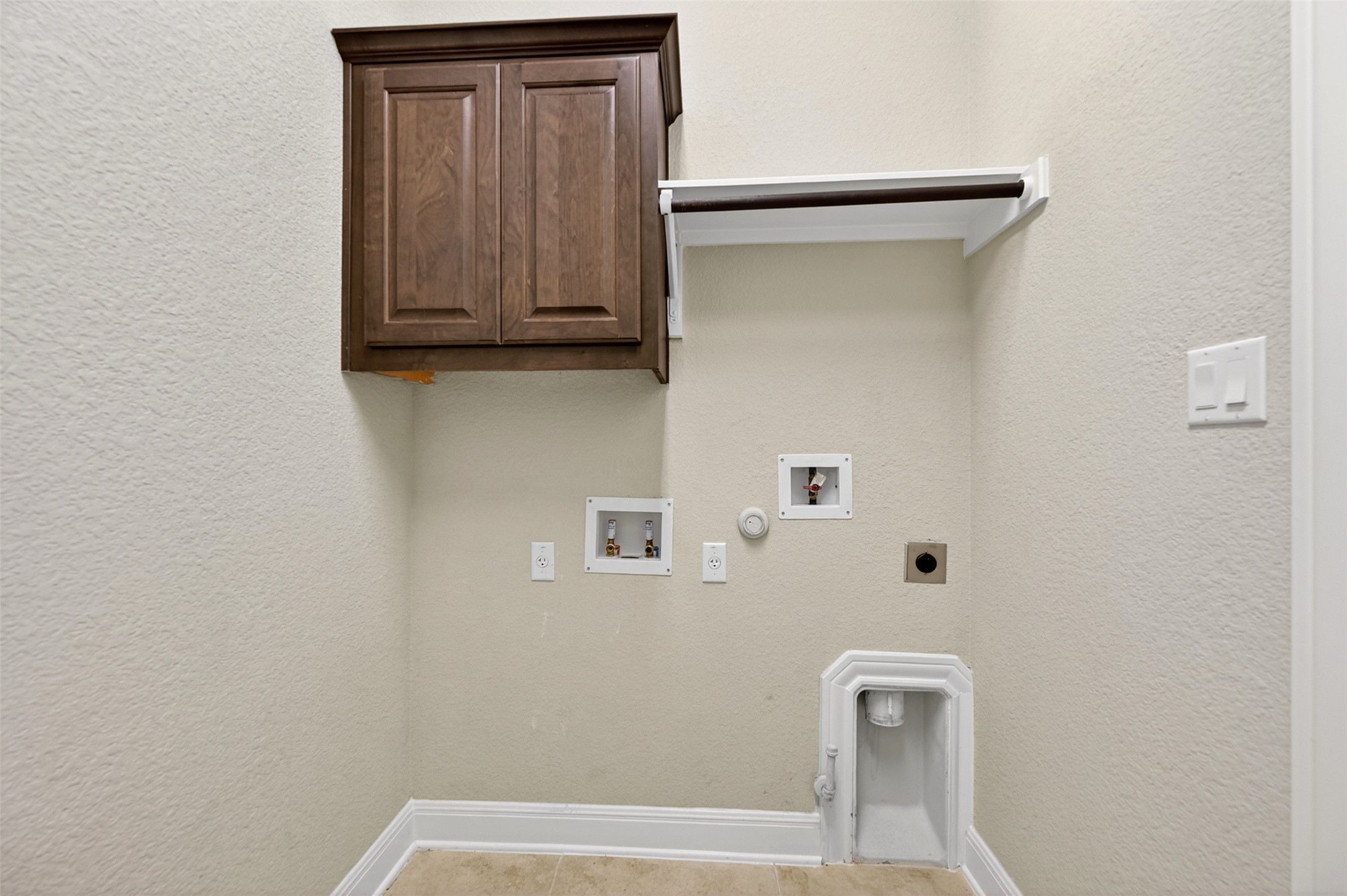 1201 Positano Pass Leander, TX 78641 - Photo 16 of 40 Utility area featuring a wood-finish cabinet, a mounted shelf, and essential appliance hookups