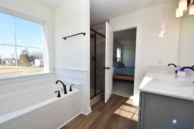 a en suite spacious bathroom with a tub double vanity and mirrors