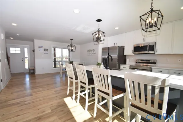 a kitchen with stainless steel appliances kitchen island granite countertop a table chairs in it and wooden floors