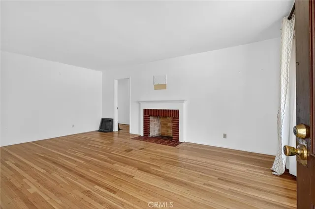 a view of empty room with wooden floor and fireplace