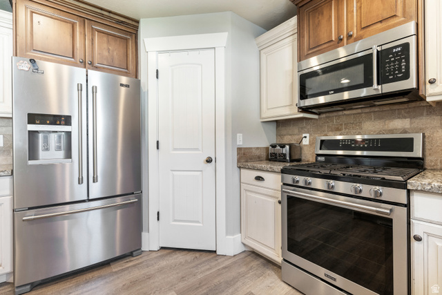 580 Cherry Ridge Lane Richmond, UT 84333 - Photo 14 of 53 Kitchen with stainless steel appliances, decorative backsplash, light wood finished floors, and light stone counters