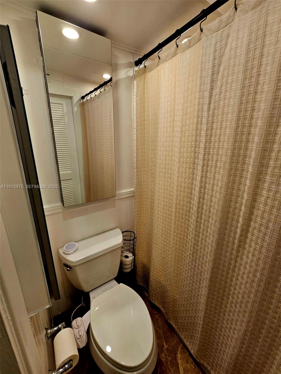 1800 North Andrews Avenue, Unit 2H Fort Lauderdale, FL 33311 - Photo 45 of 60 a white toilet sitting next to a shower curtain
