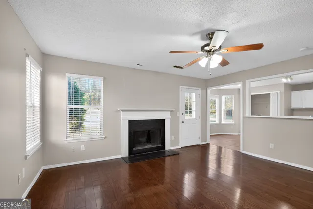 a view of an empty room with window and wooden floor