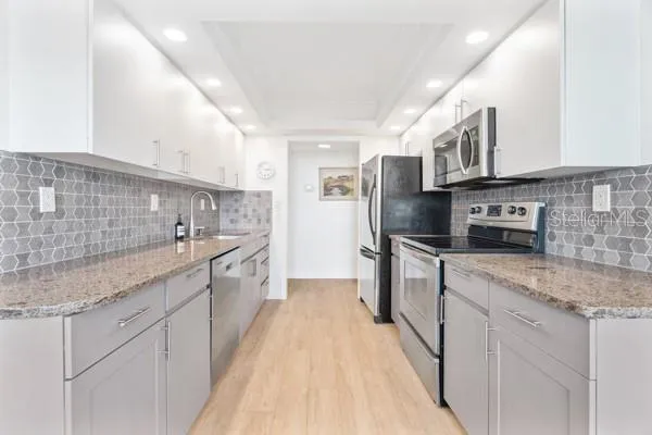 a kitchen with stainless steel appliances granite countertop a sink stove and refrigerator