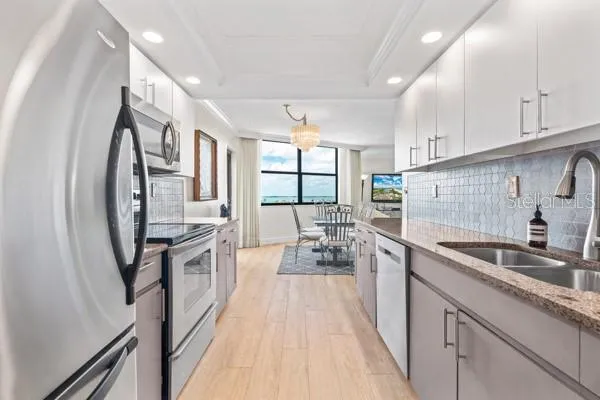 a kitchen with granite countertop a sink a counter space cabinets and stainless steel appliances