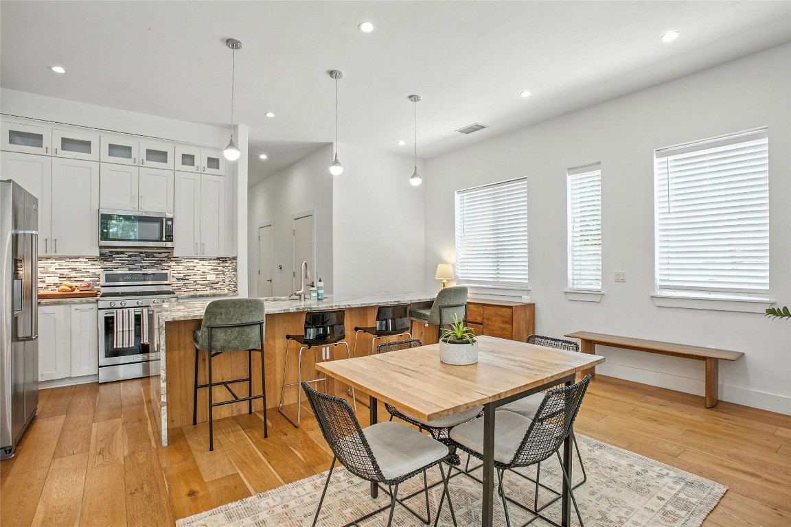 5402 Woodrow Avenue, Unit B Austin, TX 78756 - Photo 13 of 36 a kitchen with stainless steel appliances kitchen island granite countertop a stove a sink a dining table and chairs