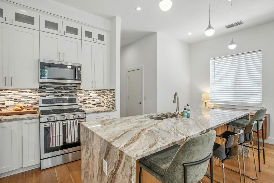 5402 Woodrow Avenue, Unit B Austin, TX 78756 - Photo 15 of 36 a kitchen with granite countertop a stove a sink and chairs