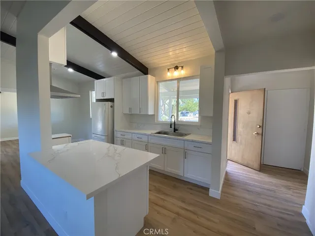 a kitchen with stainless steel appliances a kitchen island hardwood floor sink and wooden cabinets