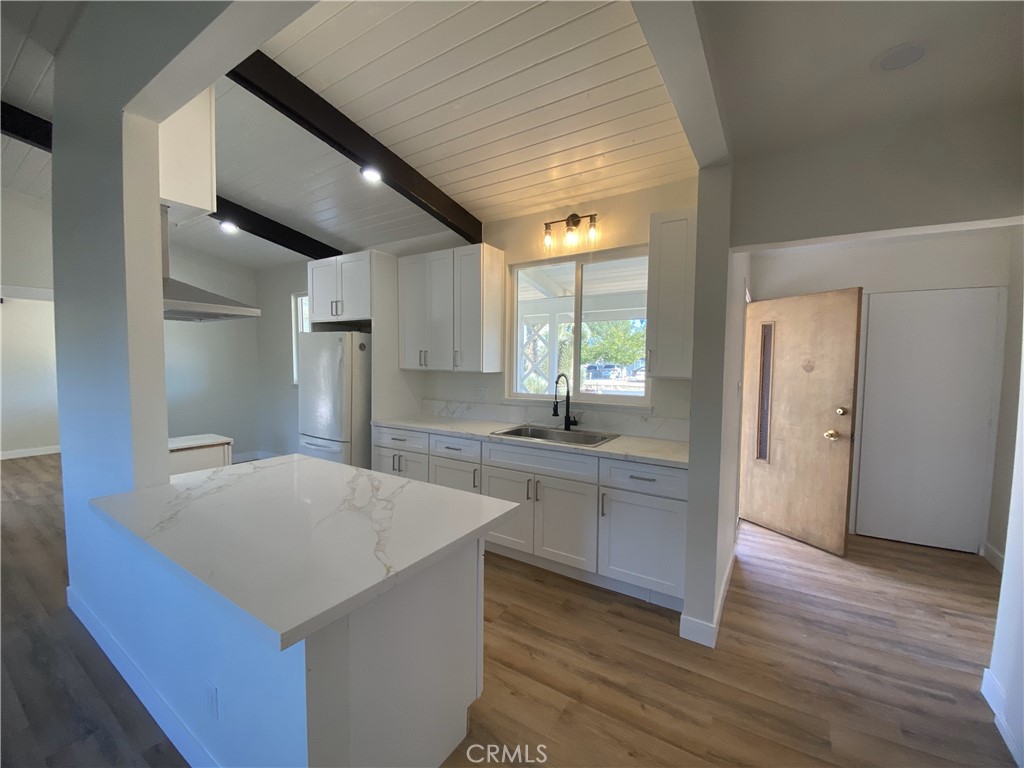 13100 Skiomah Road Apple Valley, CA 92308 - Photo 6 of 19 a kitchen with stainless steel appliances a kitchen island hardwood floor sink and wooden cabinets