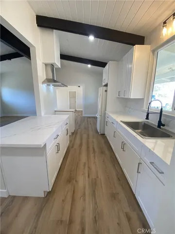 a large white kitchen with wooden floors and stainless steel appliances