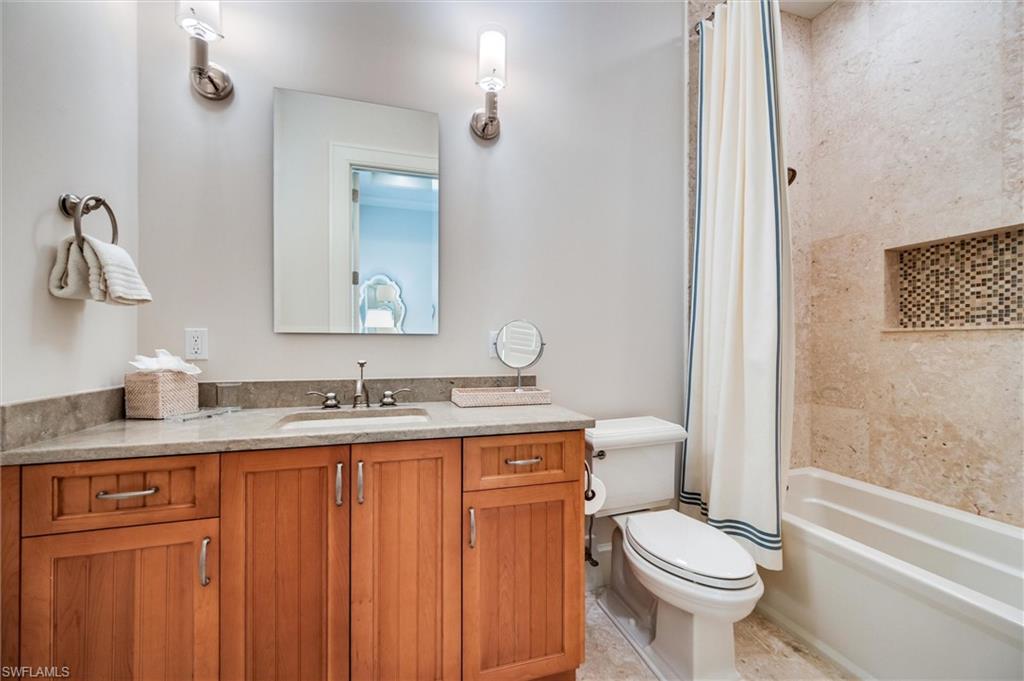 2250 Crayton Road Naples, FL 34103 - Photo 34 of 45 a bathroom with a granite countertop toilet a sink and a mirror